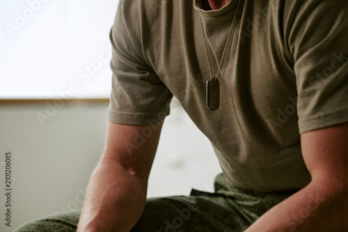 Obraz na płótnie Close up of young adult man in military hospital sitting and leaning forward, suggesting recovery and service member care