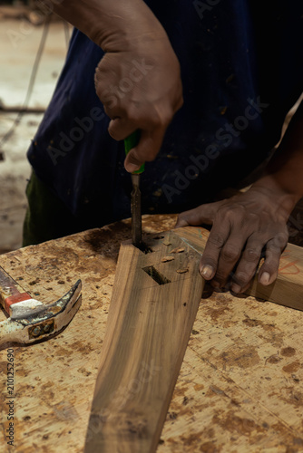 Fotografía Woodworker hands using a chisel to carve a mortise joint in a teak wood block