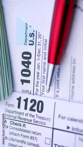 US Tax Forms and Dollar Bills. Close-up view of income tax documents with cash and a red pen during smooth camera movement.
