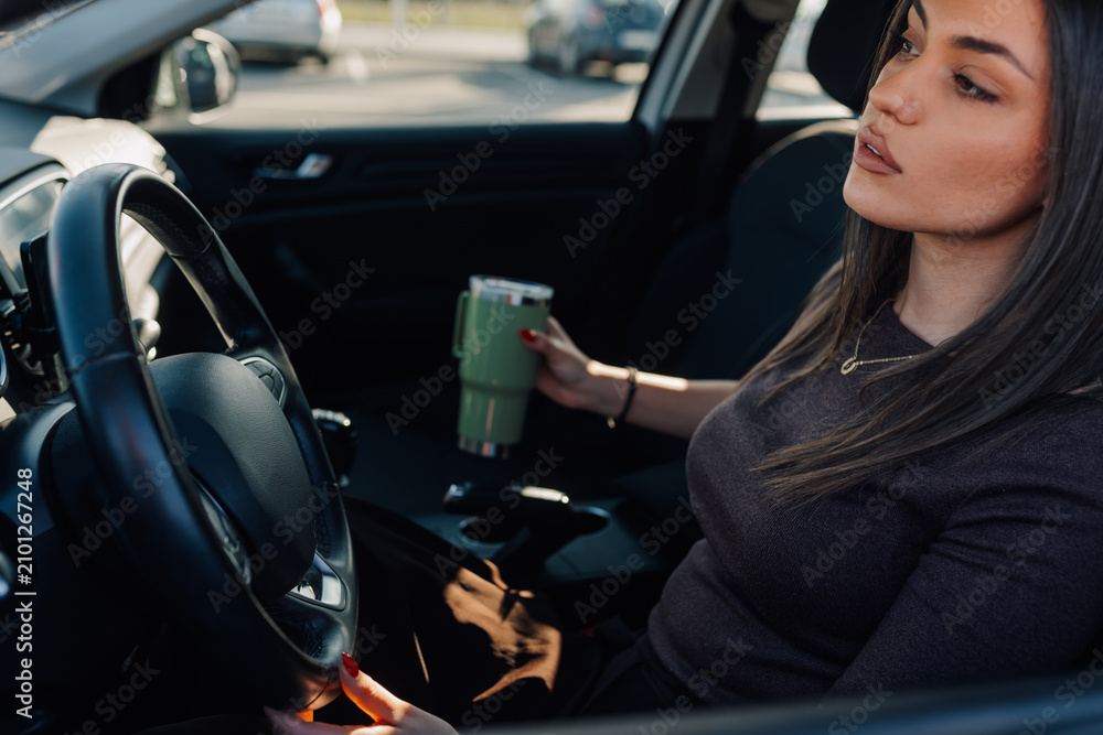 Fototapeta premium Woman driving car holding insulated cup commuting