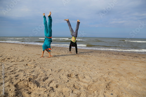 Couple jumping mid-air beach, man woman airborne dynamic movement