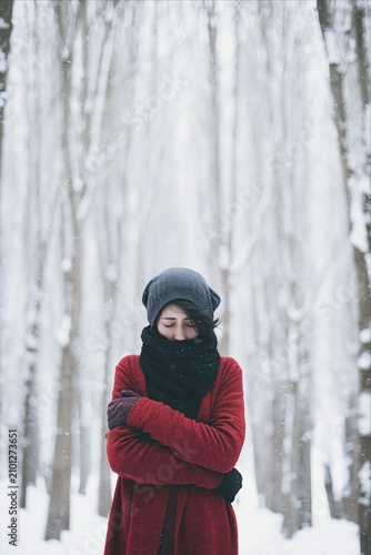 Woman in red coat feeling cold in winter snow