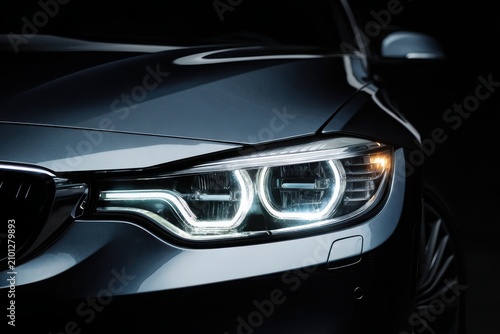 Close-up of a modern car front with illuminated LED headlight in a dark studio, highlighting premium automotive design and sleek styling.