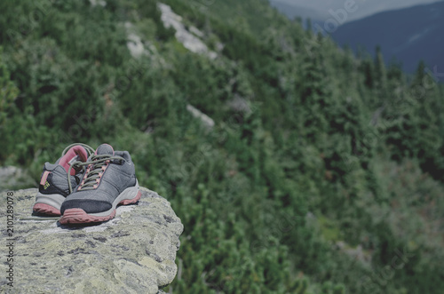Forest and mountains. Trekking sneakers on the rock. Tourist equipment