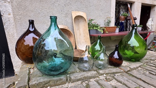 Schilderij op canvas Vintage glass demijohns and rustic wooden troughs in old town