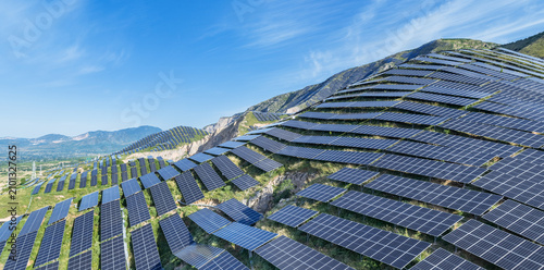 Large-Scale Solar Photovoltaic Farm Installed on Mountain Slopes Under Clear Blue Sky