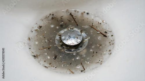 Gross bathroom sink drain clogged with hair and household debris