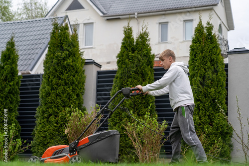 Bild auf Leinwand Determined Young Man Mowing Lawn with Electric Mower in Lush Suburban Backyard D