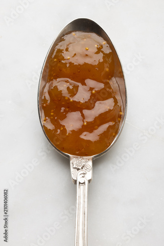 Macro detail of traditional fig jam served on a vintage silver spoon, highlighting rich texture, homemade quality, and Mediterranean culinary tradition.