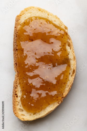 Macro detail of a slice of rustic bread topped with fig jam, highlighting rich texture, homemade sweetness, and traditional Mediterranean breakfast flavors.