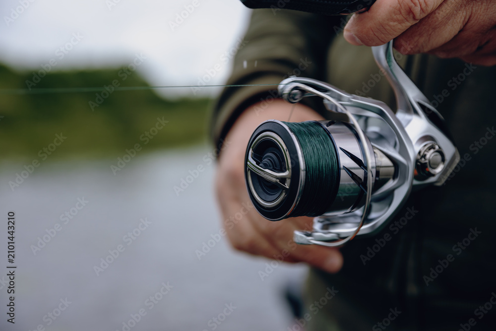 Fototapeta premium A spinning rod with a spinning reel in the hands of a fisherman