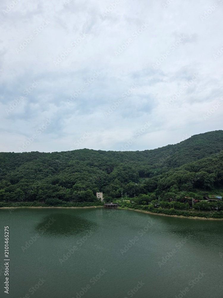 Fototapeta premium 남양주 오남저수지의 여름, 초록이 짙은 산과 강, 하늘과 구름, 멋진 자연 배경