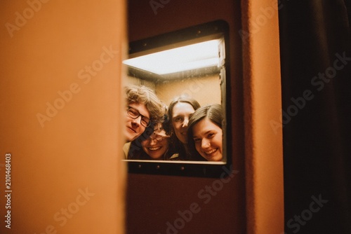 Friends Laughing Inside a Vintage Photo Booth with Warm Lighting and Authentic Candid Emotions