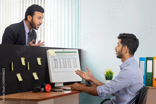 An angry boss in formal suit and a subordinate corporate employee arguing at the workdesk.