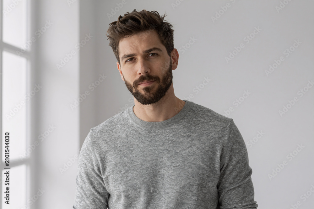 Fototapeta premium Confident man with beard in gray sweater looking at camera