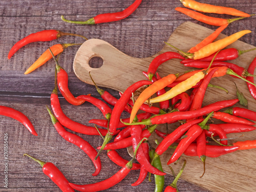 Картината върху платно Fresh red chili peppers in a wooden bowl on a rustic wooden table with a cutting board, top view