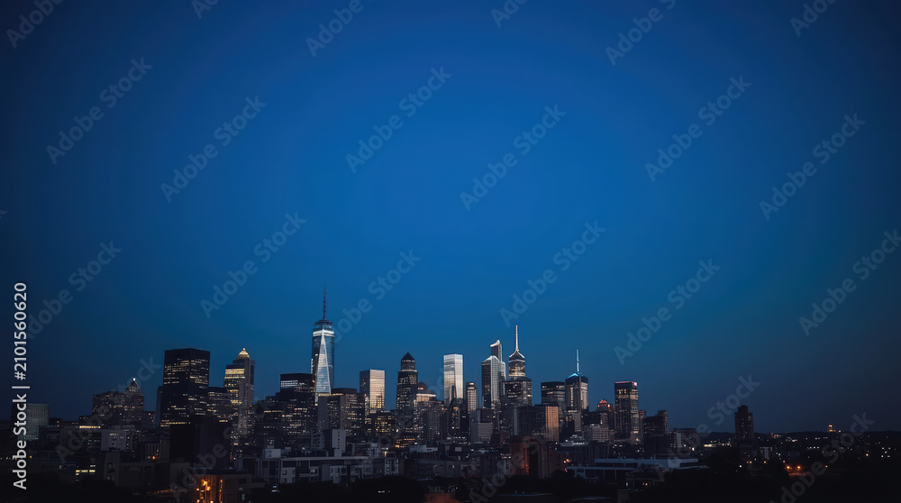 Fototapeta premium Modern city skyline at blue hour with illuminated skyscraper silhouette
