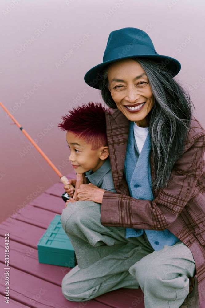 Fototapeta premium Playful grandmother and grandson fishing on a painted dock for poster and background use showing multigenerational bond and relaxed outdoor activity