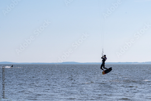 Foto Skilled kitesurfer performs an impressive high jump above the deep blue ocean wa