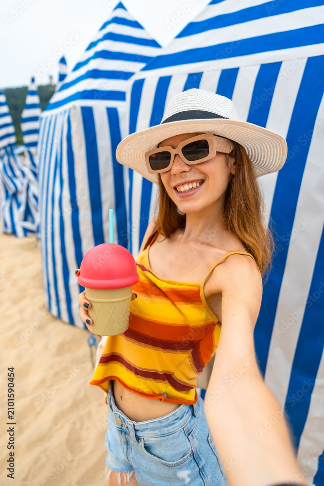Obraz premium Woman enjoying beach vacation taking selfie with drink