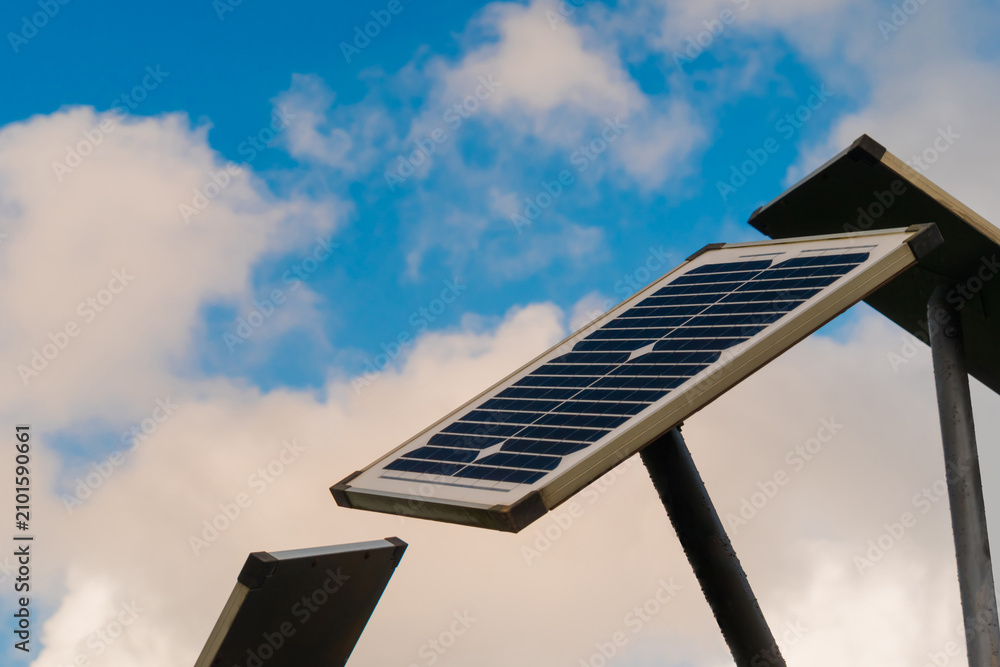 Obraz premium Solar panels against white clouds in the blue sky - close up view. Renewable energy, alternative source of electricity, technology, and ecological concept