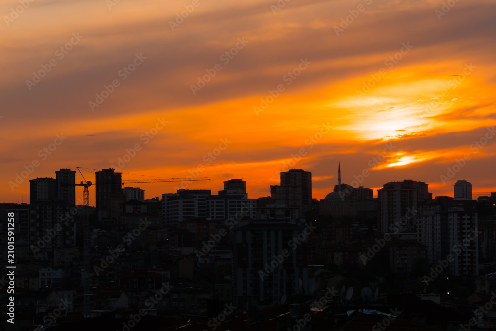 Fototapeta premium Dramatic sunset sky with the setting sun over the city of Istanbul, Turkey in the evening - apartment, residential buildings silhouettes. Summer, architecture, urban and cityscape concept