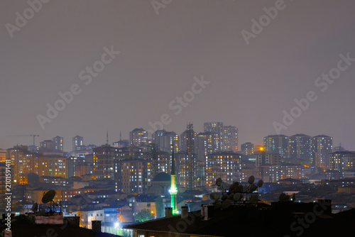 Canvas Print Dark sky over typical turkish apartment, residential buildings with warm lightin