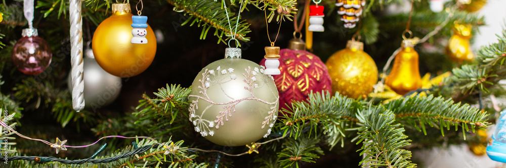 Obraz premium A Christmas tree stands with many colorful ornaments hanging from its branches. Each ornament shows different shapes and colors, celebrating the festive season and bringing joy to the home