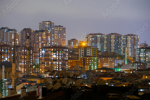 View of typical turkish multistory residential buildings with illuminated windows and warm street lighting in Istanbul, Turkey at night. Cityscape and urban concept