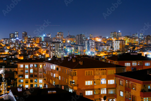 View of typical turkish multistory residential buildings with illuminated windows and warm street lighting in Istanbul, Turkey at night. Architecture concept