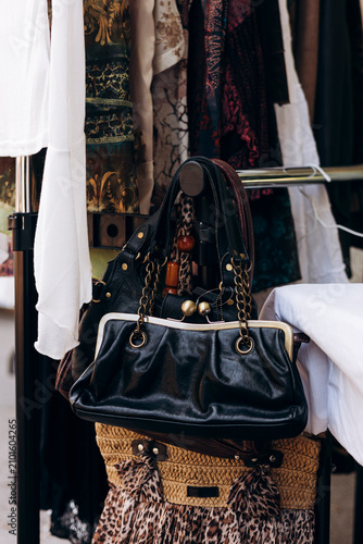 Vintage leather handbags and clothing at flea market stall.