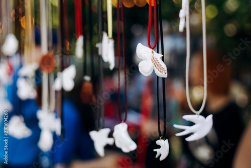 Colorful handmade ceramic jewelry hanging on display at an outdoor craft fair.