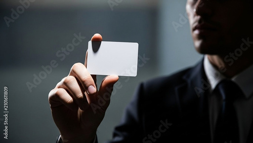 Man in Suit Holds Blank Business Card in Dramatic Light
