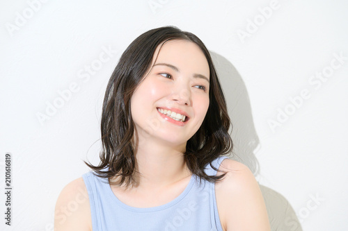 白背景で日差しを浴びる日本人女性のビューティイメージ