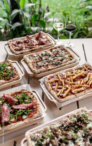 many different Pinsa types on garden restaurant pizza slice buffet table outdoors