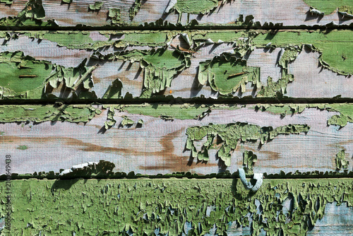 Rustic wood boards with flaking green paint revealing purple-gray weathered wood underneath