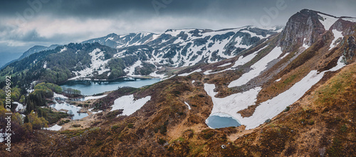 Fotografie High altitude mountain landscape with melting snow, rocky terrain, and serene al