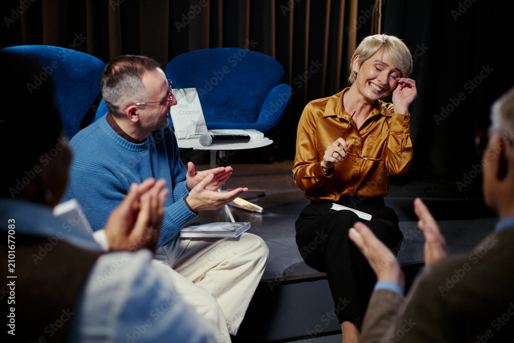 Obraz premium Middle aged business group applauding smiling Caucasian woman speaking during panel discussion, showing recognition and teamwork. Ideal for leadership, corporate event, communication use