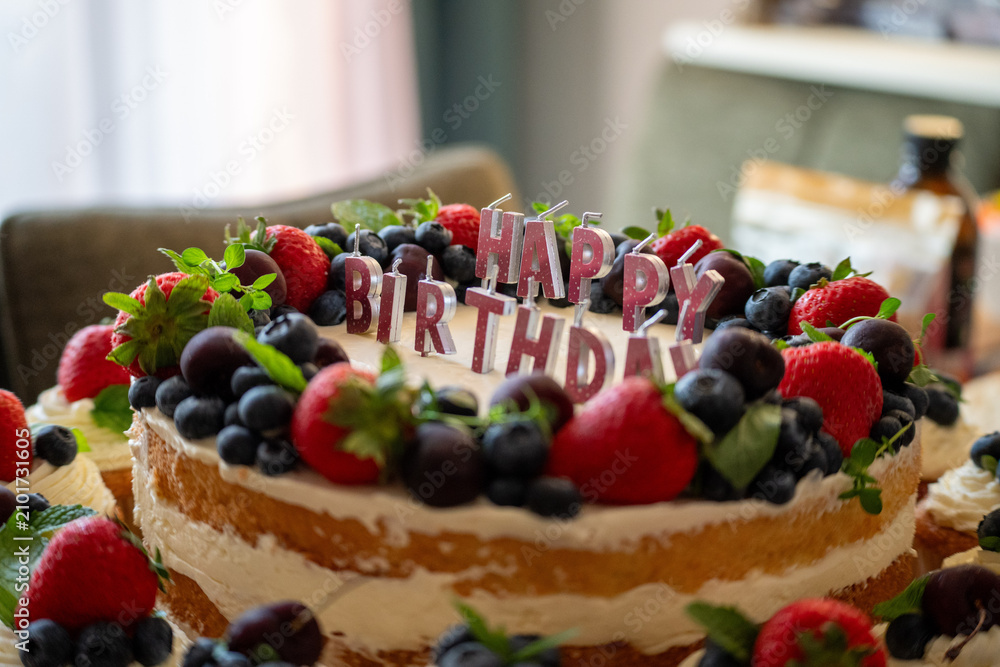 Fototapeta premium Birthday cake decorated with berries and happy birthday candles