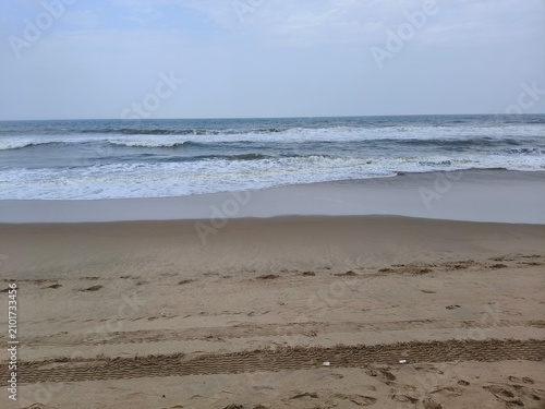 Quadro su tela Atmospheric beach scene with ocean waves and tire marks on wet sand shoreline se