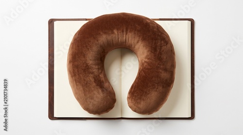 Comfortable brown neck pillow placed on a notebook ideal for travel relaxation and comfort during your journeys