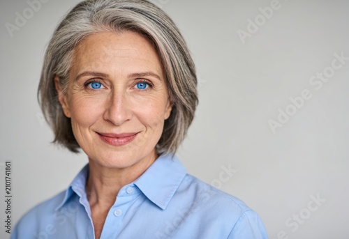 Mature woman with short gray hair and blue eyes smiling at camera