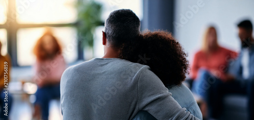 candid back view of two colleagues comforting each other during a stress management workshop
