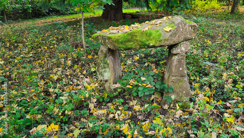 Obraz na płótnie An ancient stone dolmen covered in moss in an autumn forest