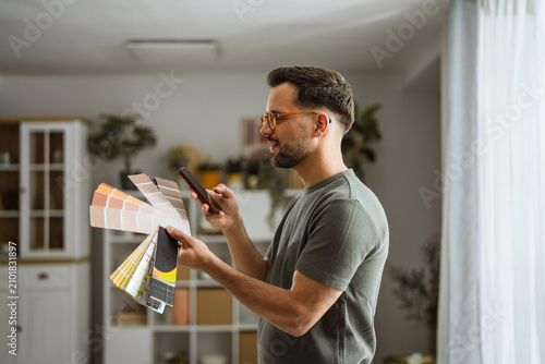 Foto Man selecting home paint colors using color palette and smartphone