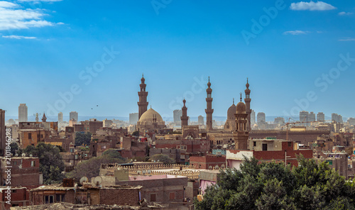 EGYPT, CAIRO: A panoramic daytime view of historic Islamic Cairo featuring ancient mosque minarets and domes under a vibrant blue sky