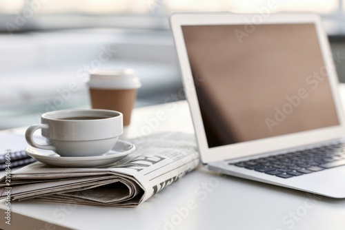 Open Laptop With Folded Newspaper in Workspace