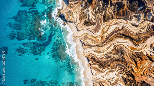 Aerial view of turquoise ocean meeting patterned coastal cliffs