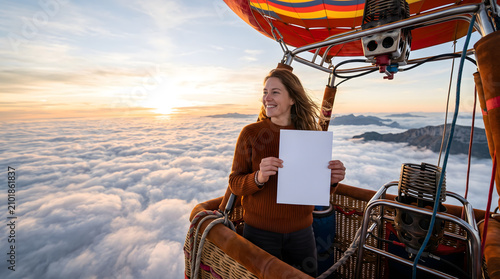Smiling woman holding blank sign in hot air balloon above the clouds