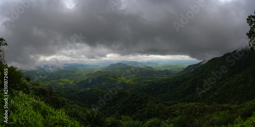 Dramatic panoramic landscape of lush green mountains under dark stormy clouds in Umphang Tak Thailand
